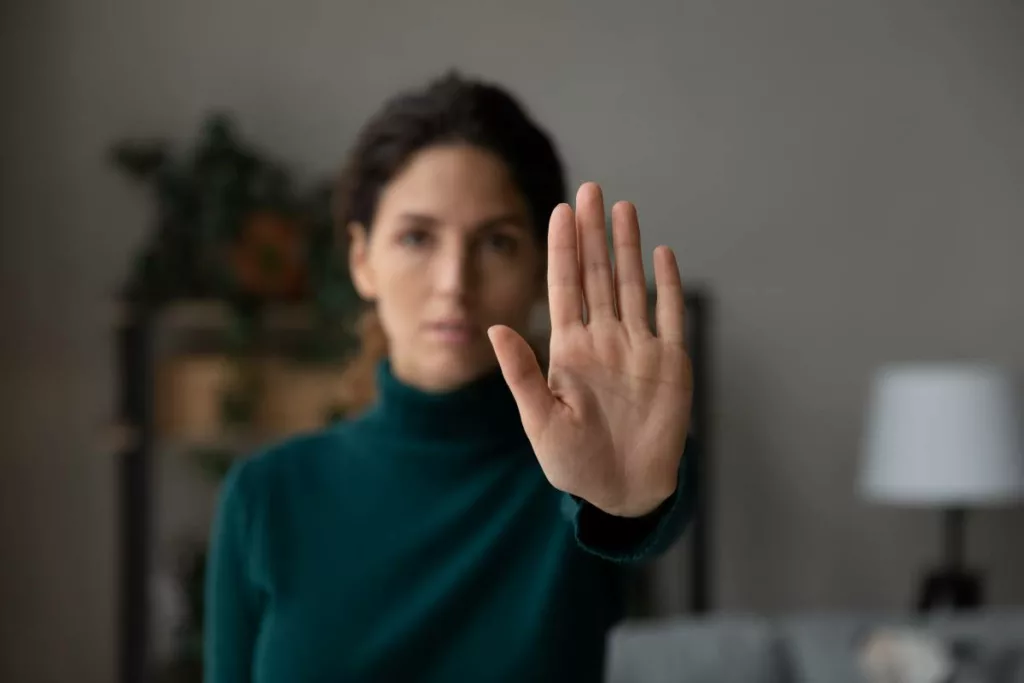 Una donna alza la mano in segno di stop, simbolo di resistenza e inizio di un nuovo capitolo lavorativo supportato dagli incentivi del programma italiano 'Sgravio contributivo per assunzioni donne vittime di violenza'