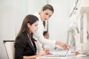 Due donne lavorano su un computer portatile in ufficio. Supporto formazione lavoro.
