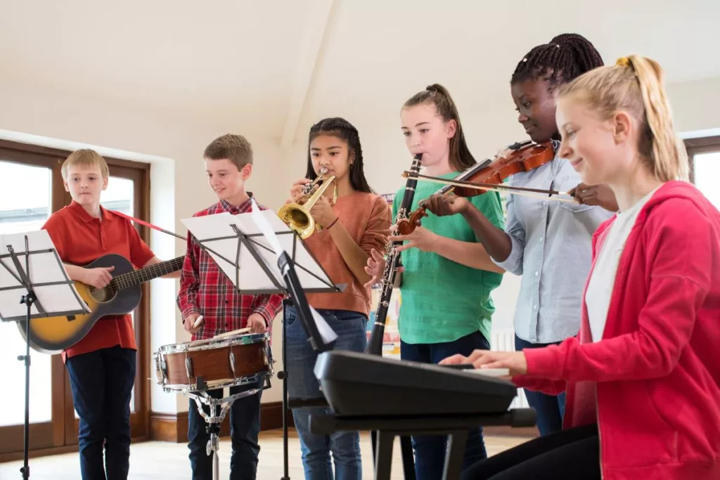 Gruppo di bambini che suonano diversi strumenti musicali insieme in una sala prove grazie a bonus musica