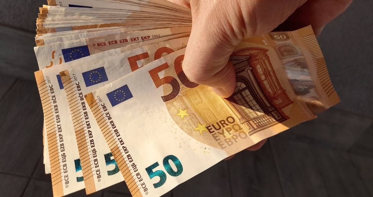 Un uomo tiene in mano banconote da 50 euro, rappresentando il concetto di quattordicesima